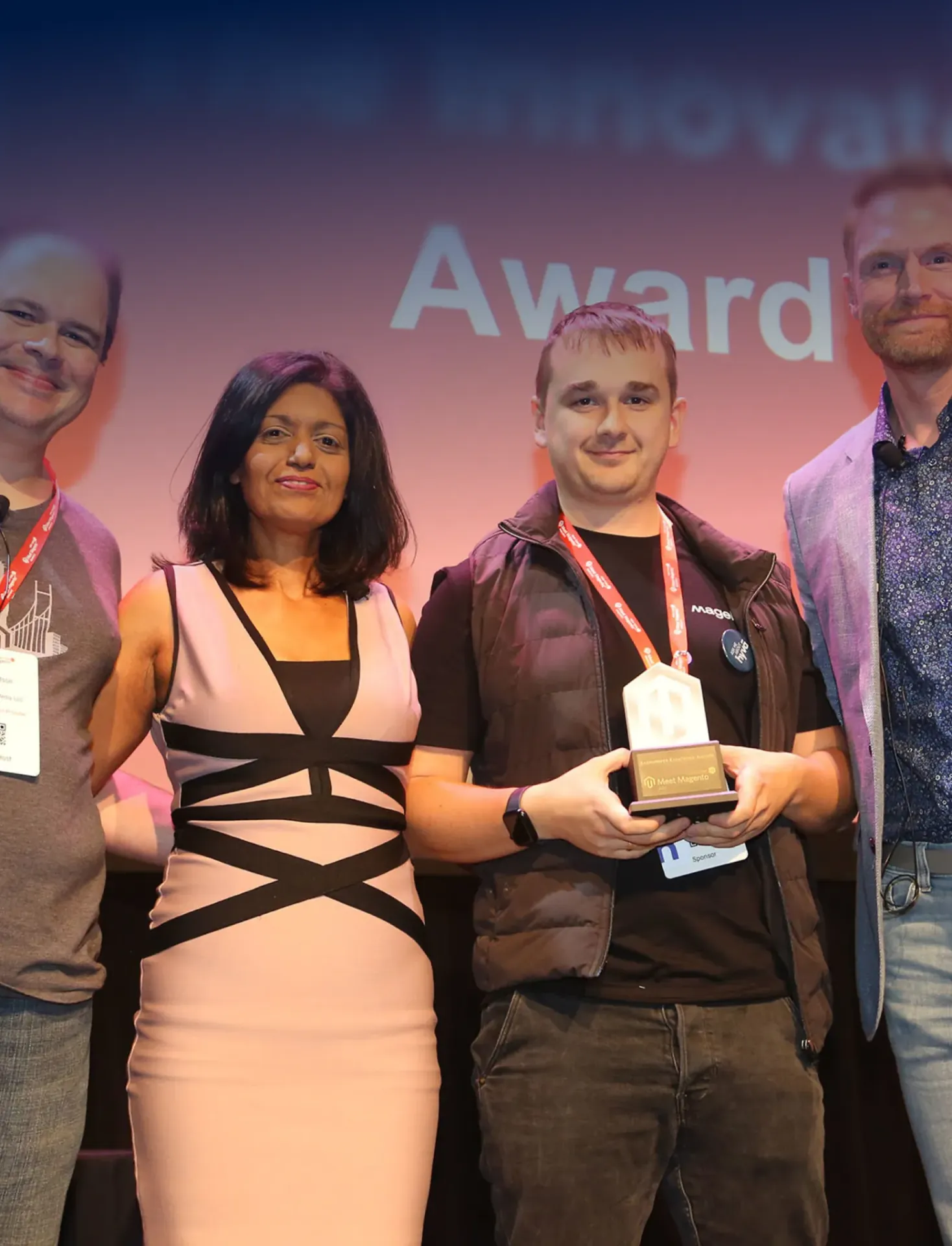 Four people at an awards event, one holding a Meet Magento trophy.