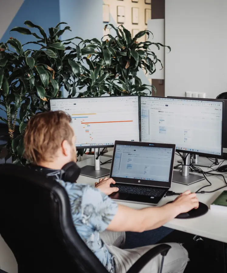 A Magebit engineer working at a multi-monitor workstation