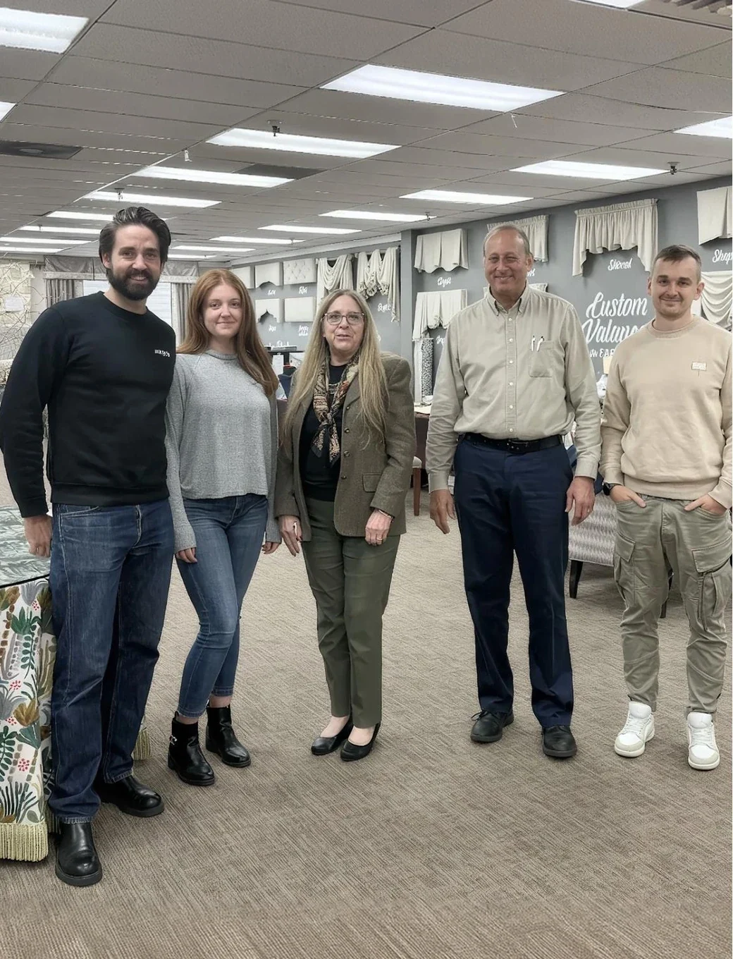 Five people standing together in The Fabric Mill's showroom, in front of curtain and valance displays.
