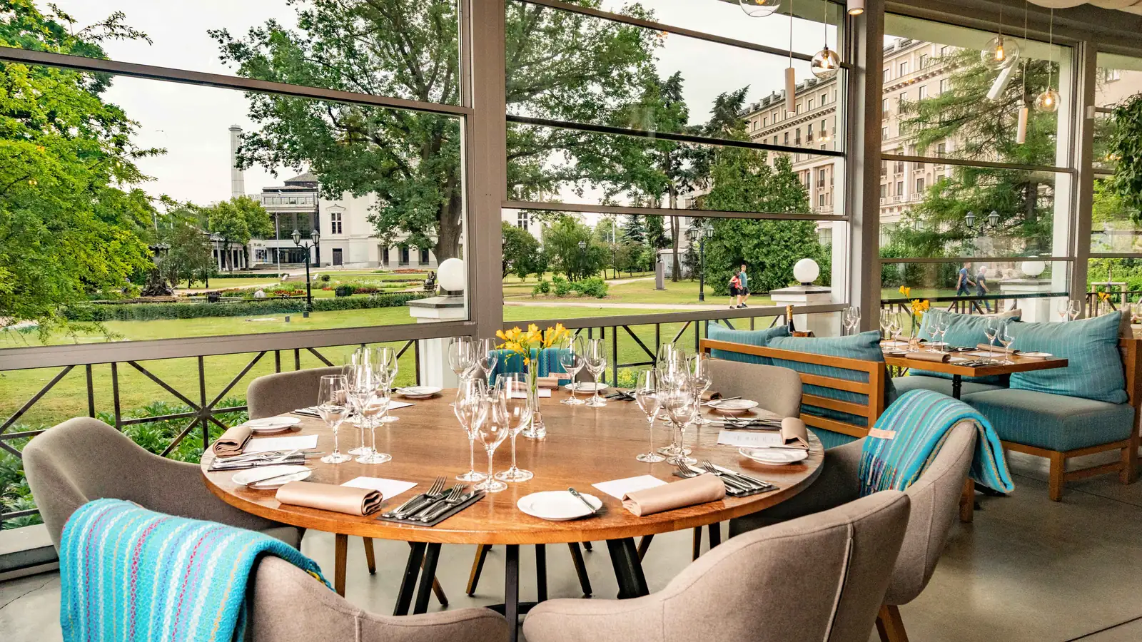 A round table at Kolonāde set for dinner, with a view of the park