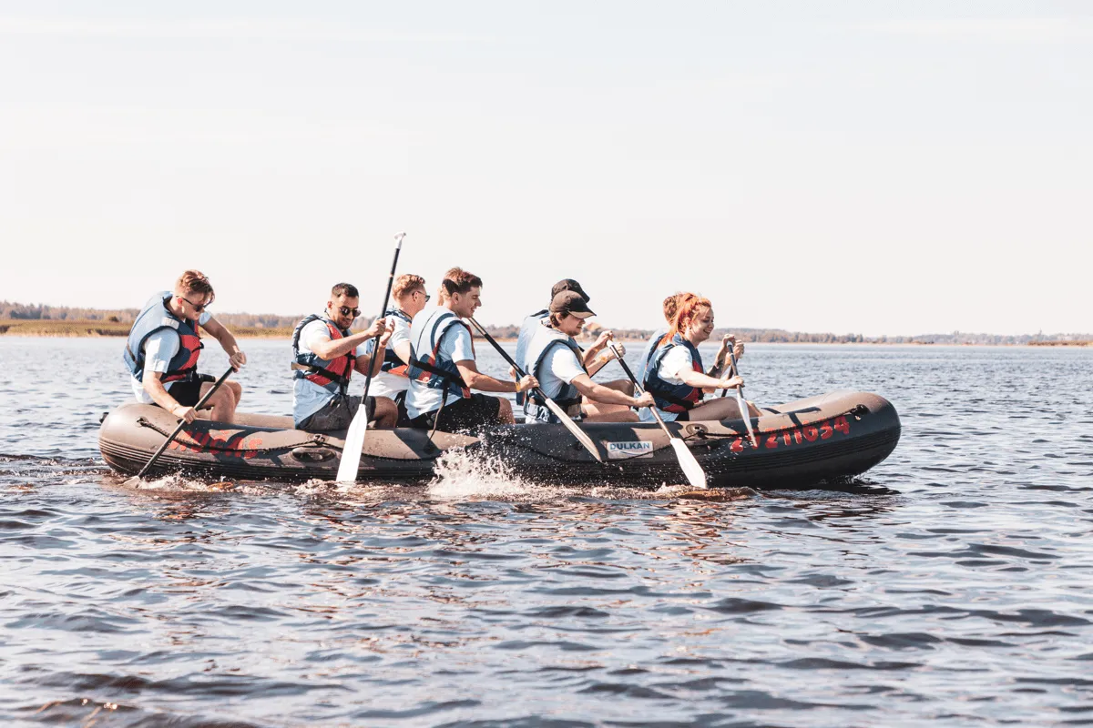 Colleagues paddling an inflatable raft on a lake