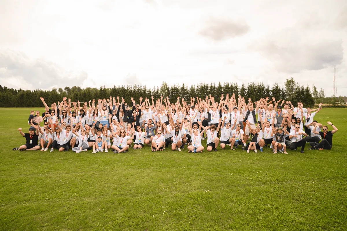The Magebit team waving in a group photo on a field