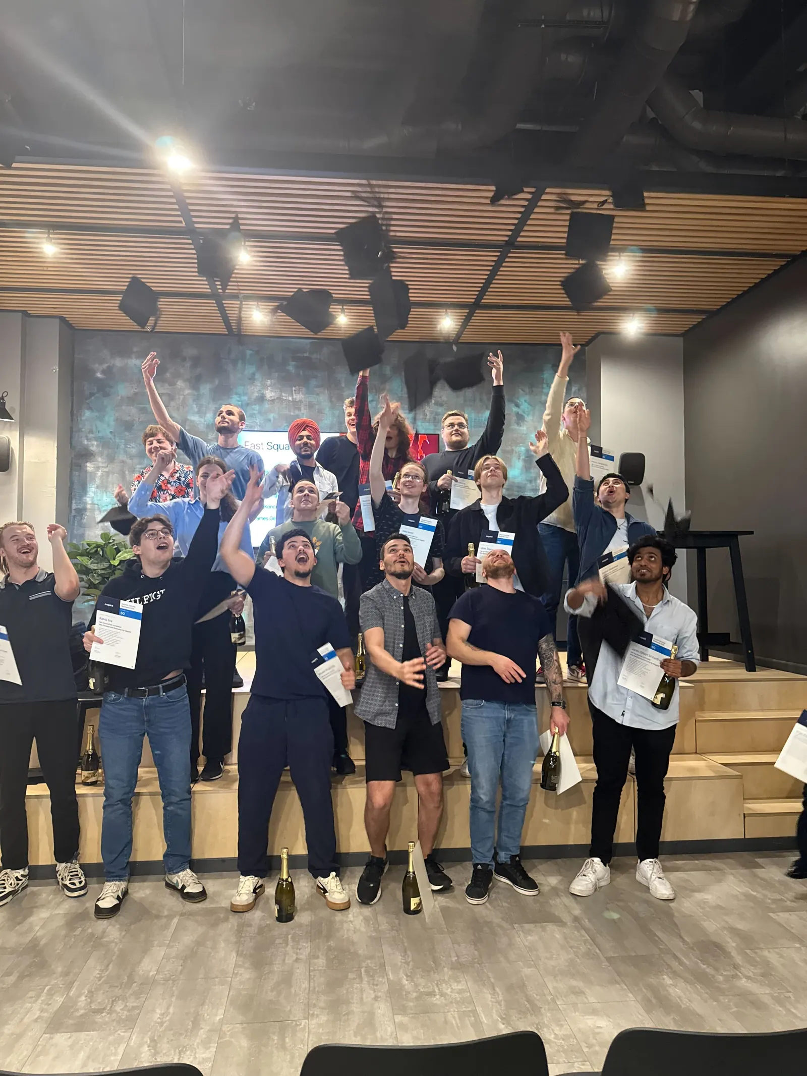 Magebit Bootcamp 2025 graduates celebrating with a cap toss, holding their certificates