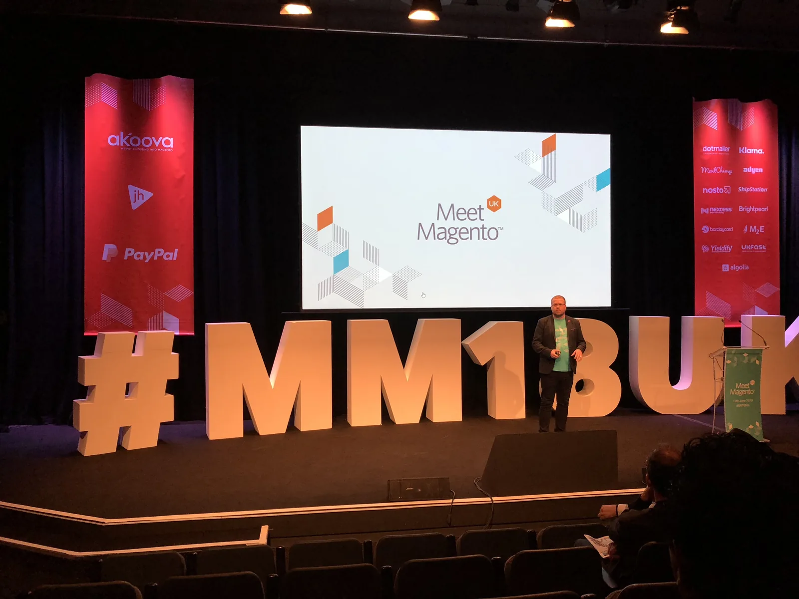 Meet Magento UK 2018 main stage with the #MM18UK letters and Meet Magento slide