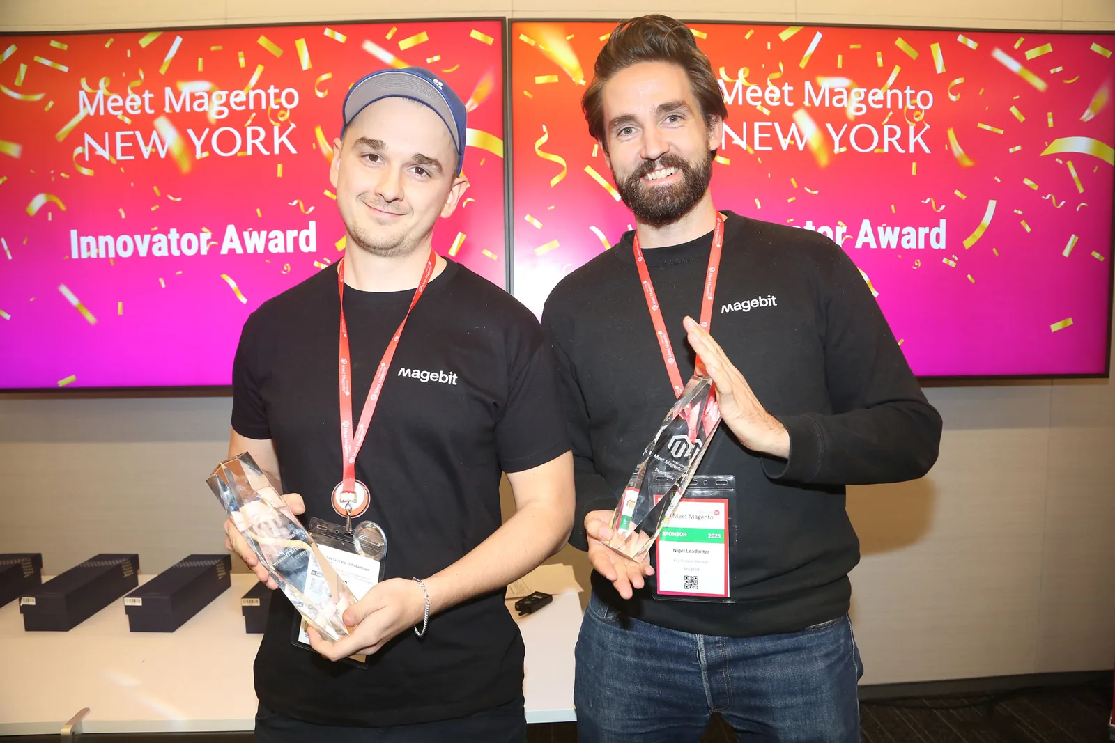Two Magebit team members holding their award trophies at Meet Magento New York 2025