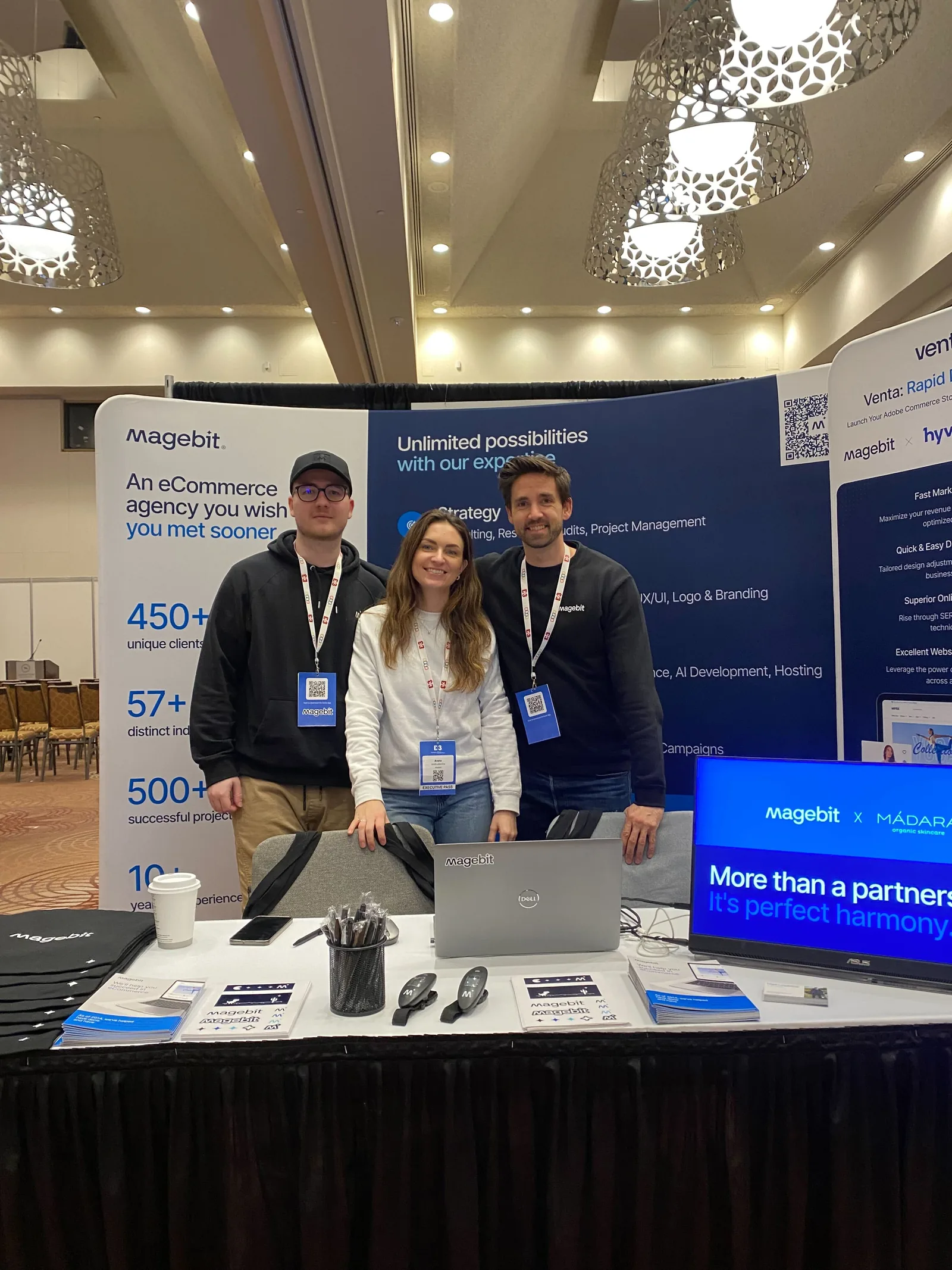 Three Magebit team members at the Magebit booth at DX3 Canada 2025, with a screen showing the Magebit and MÁDARA partnership