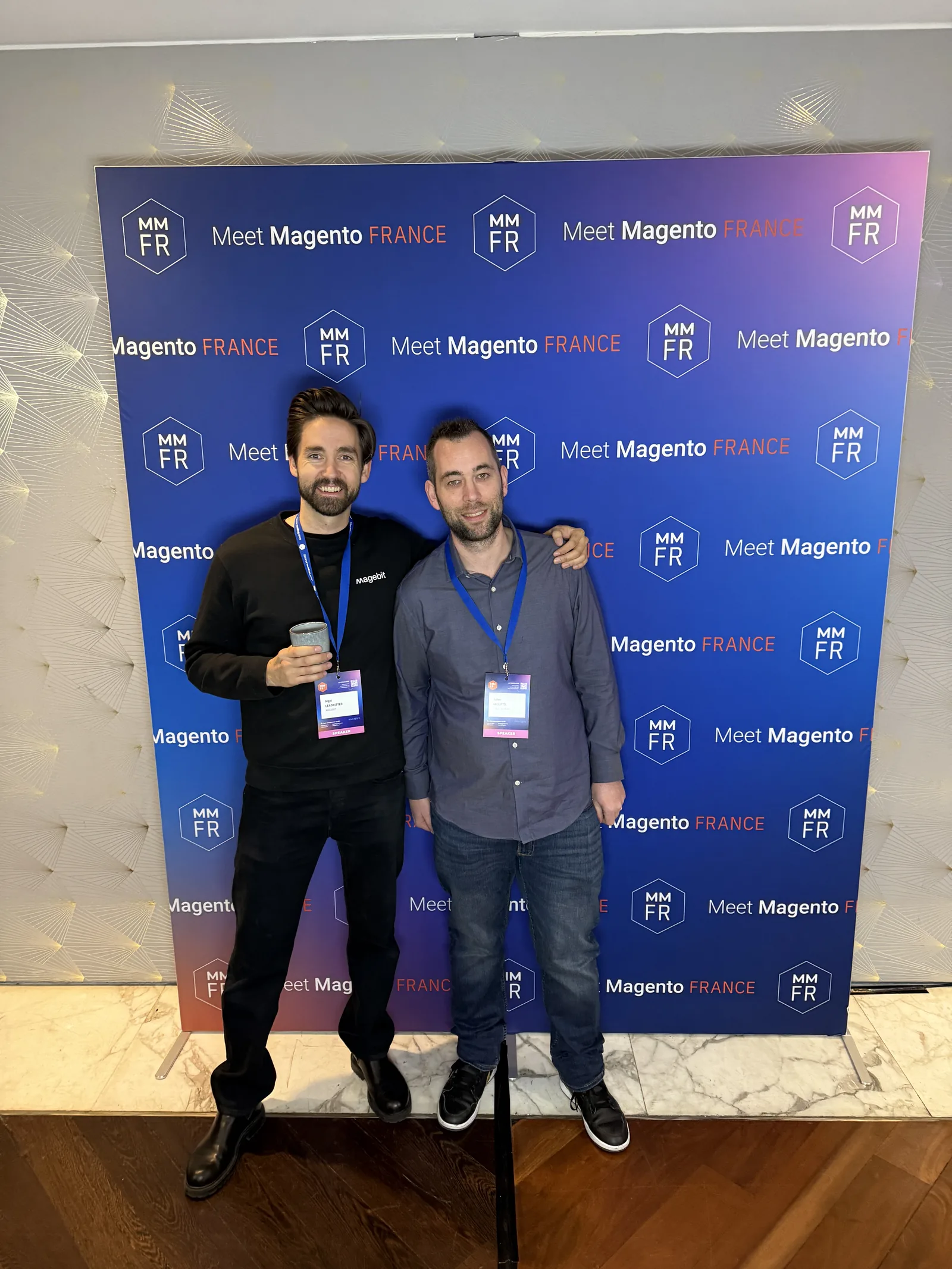 Two Magebit team members at the Meet Magento France 2025 photo wall