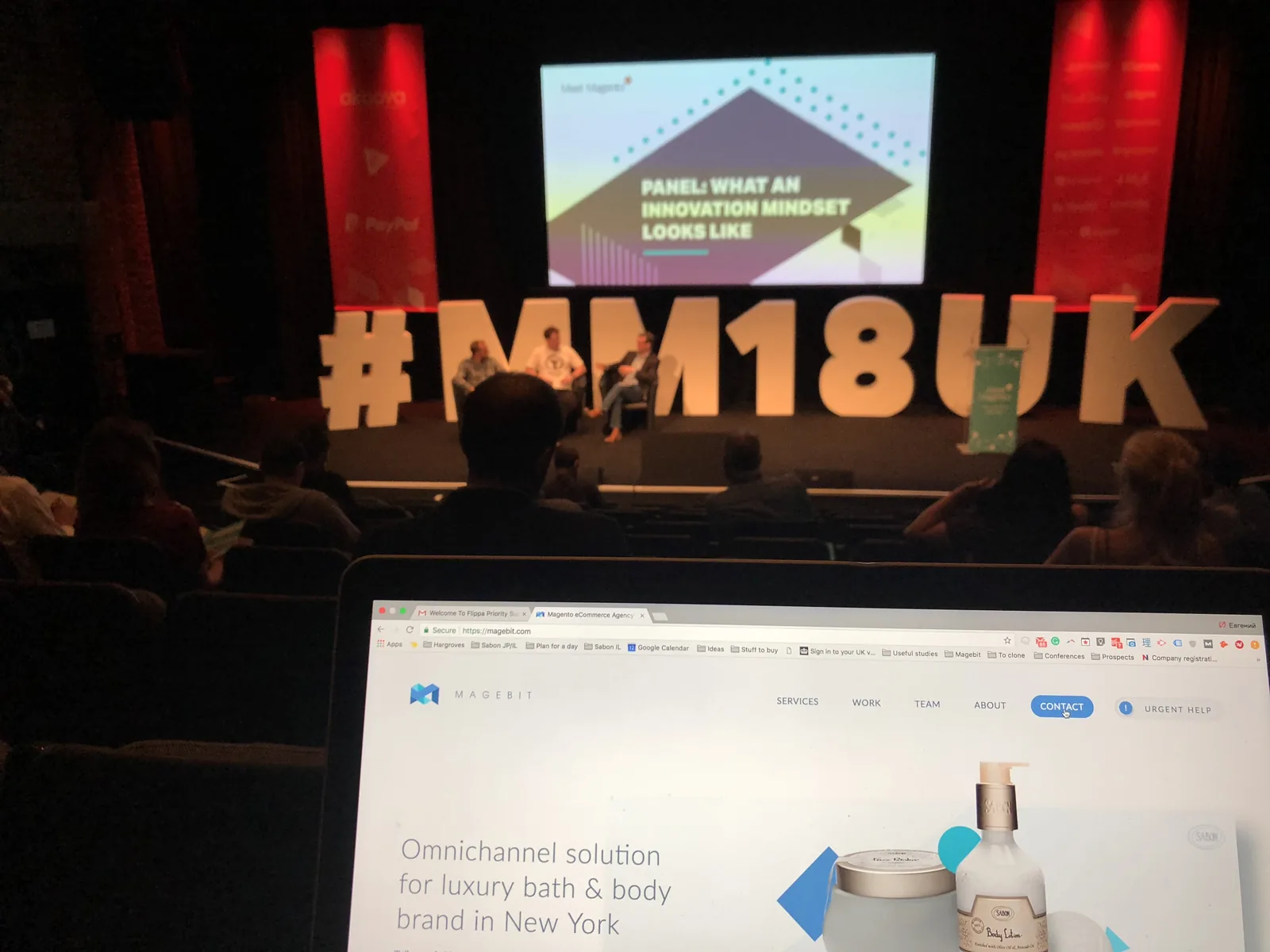 Panel on the #MM18UK stage, seen past a laptop showing the Magebit website