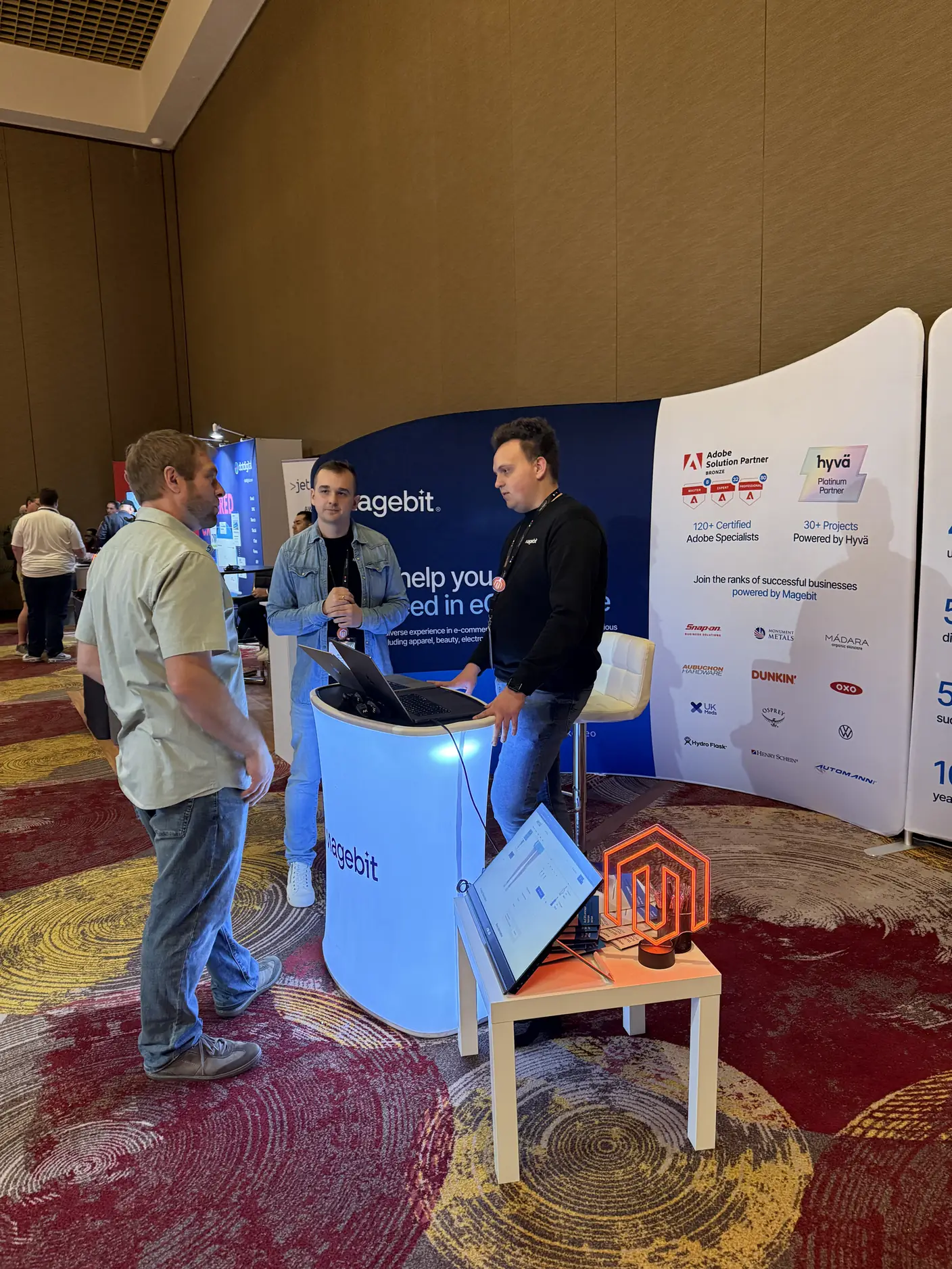 Attendees in conversation at the Magebit booth at Meet Magento Florida 2025