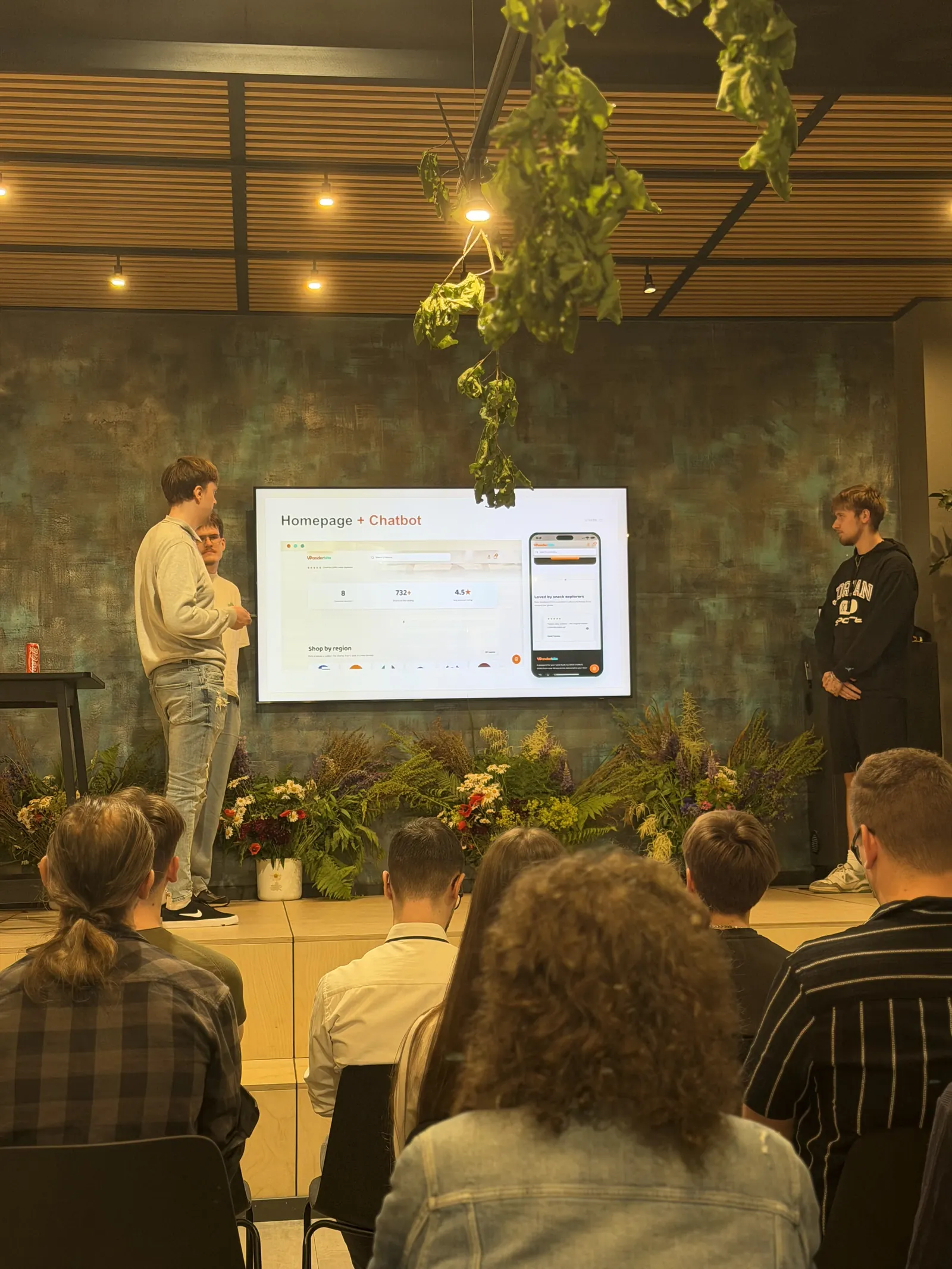 A bootcamp team presenting their e-commerce project on stage to an audience