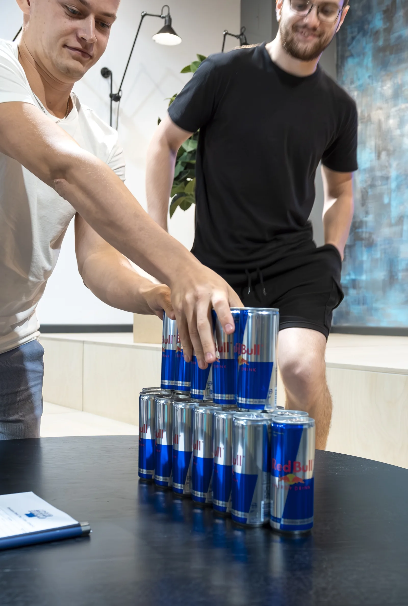 A participant stacking a pyramid of Red Bull cans in a team challenge at the Magebit IT Bootcamp 2023