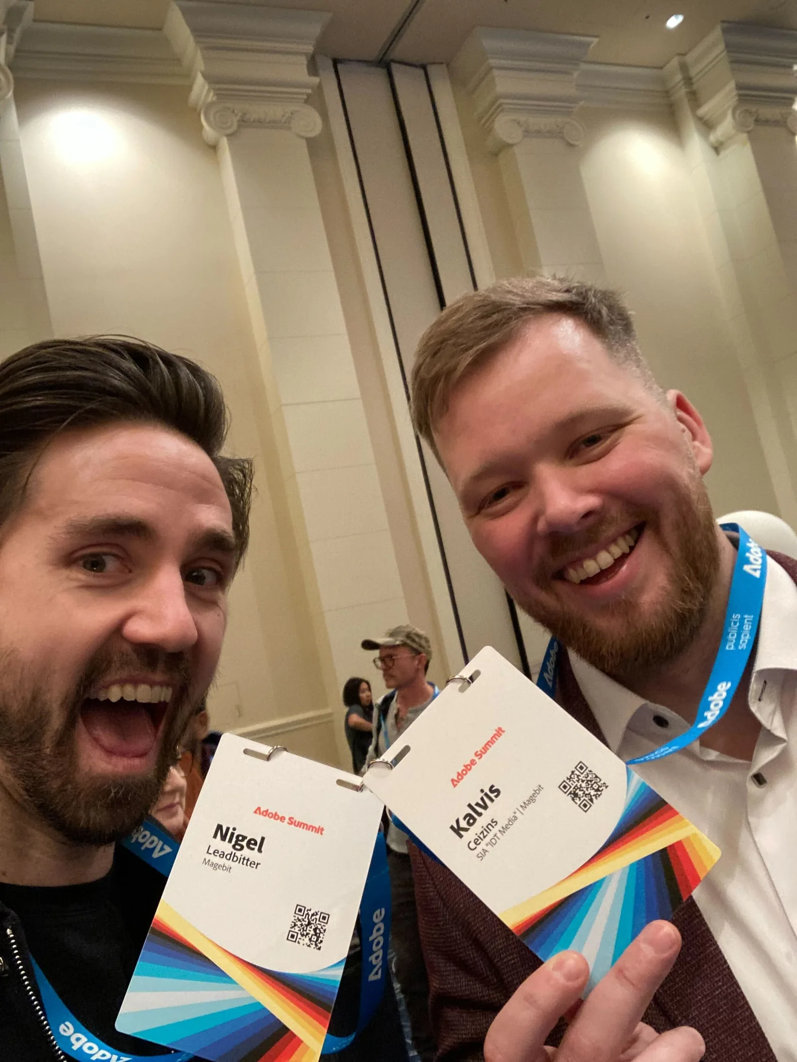Nigel Leadbitter and Kalvis Ceizins holding up their Adobe Summit 2025 badges