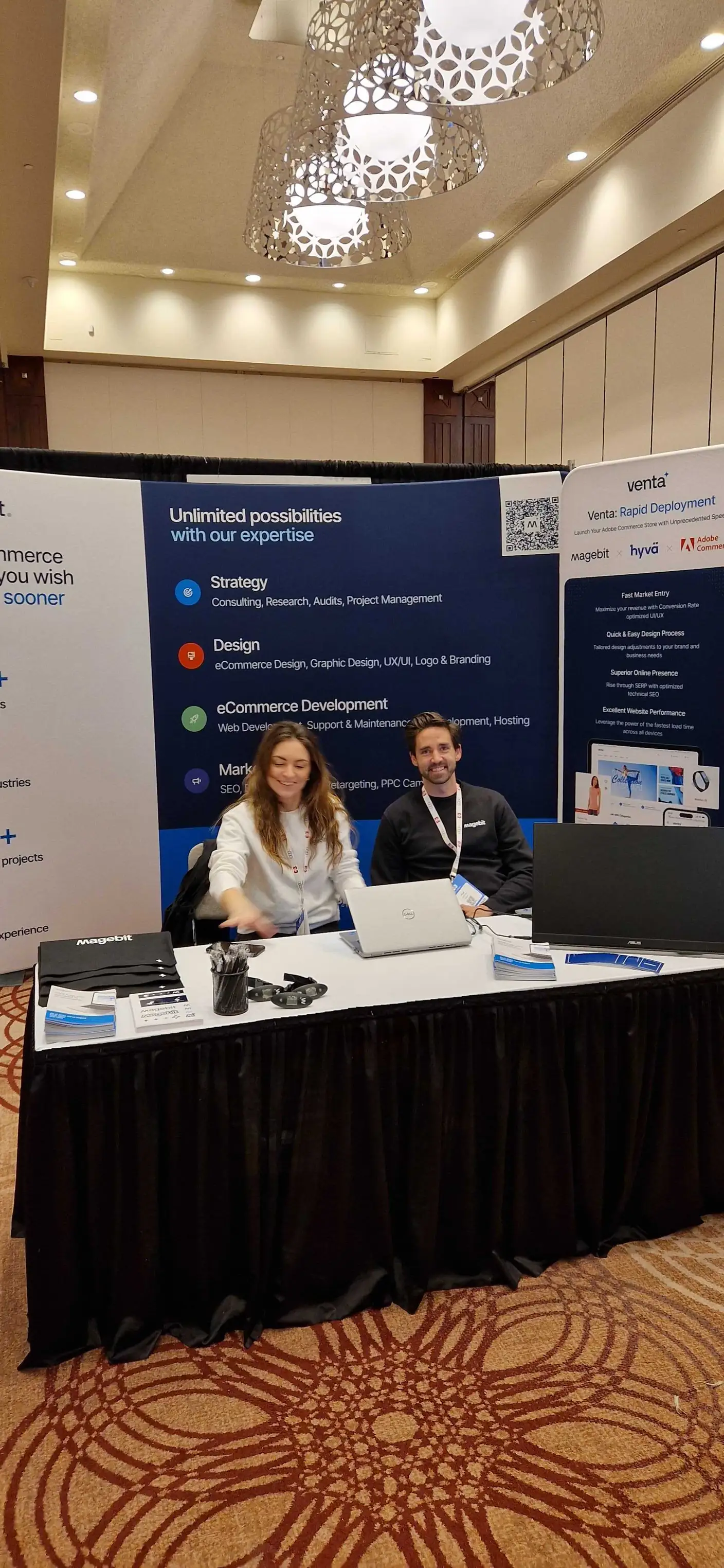 Two Magebit team members seated at the booth in front of the strategy, design, development and marketing backdrop at DX3 Canada 2025