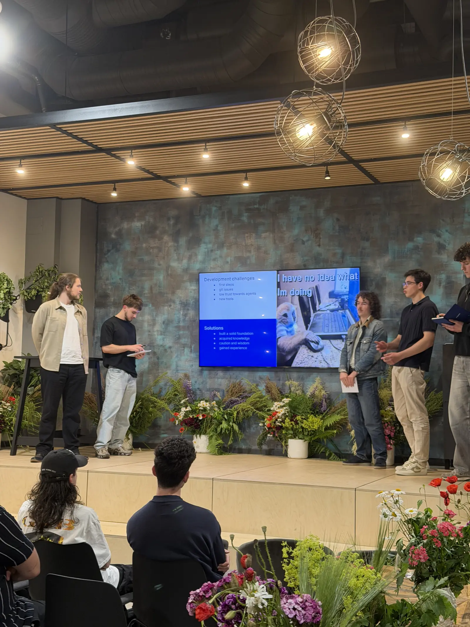A bootcamp team on stage demoing their project on two large screens during final presentations
