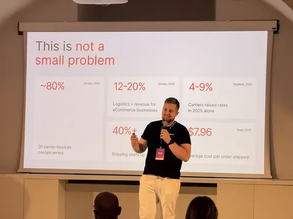 Rihards R. of Magebit presenting shipping profitability figures on stage at Meet Magento Italy 2026