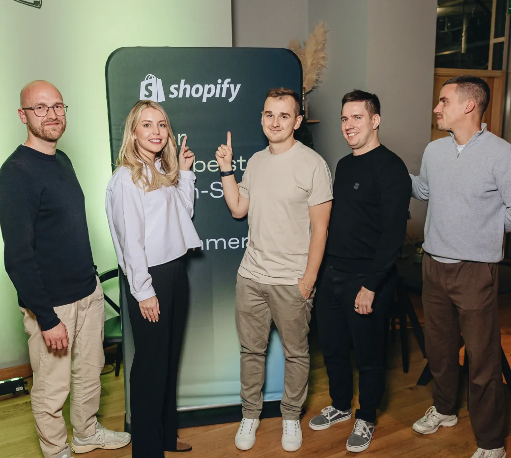 The Magebit team hosting the Shopify Dinner, in front of a Shopify banner