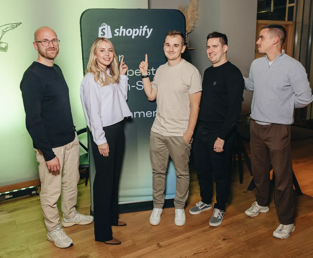 Five members of the Magebit team beside a Shopify stand at an ecommerce conference.